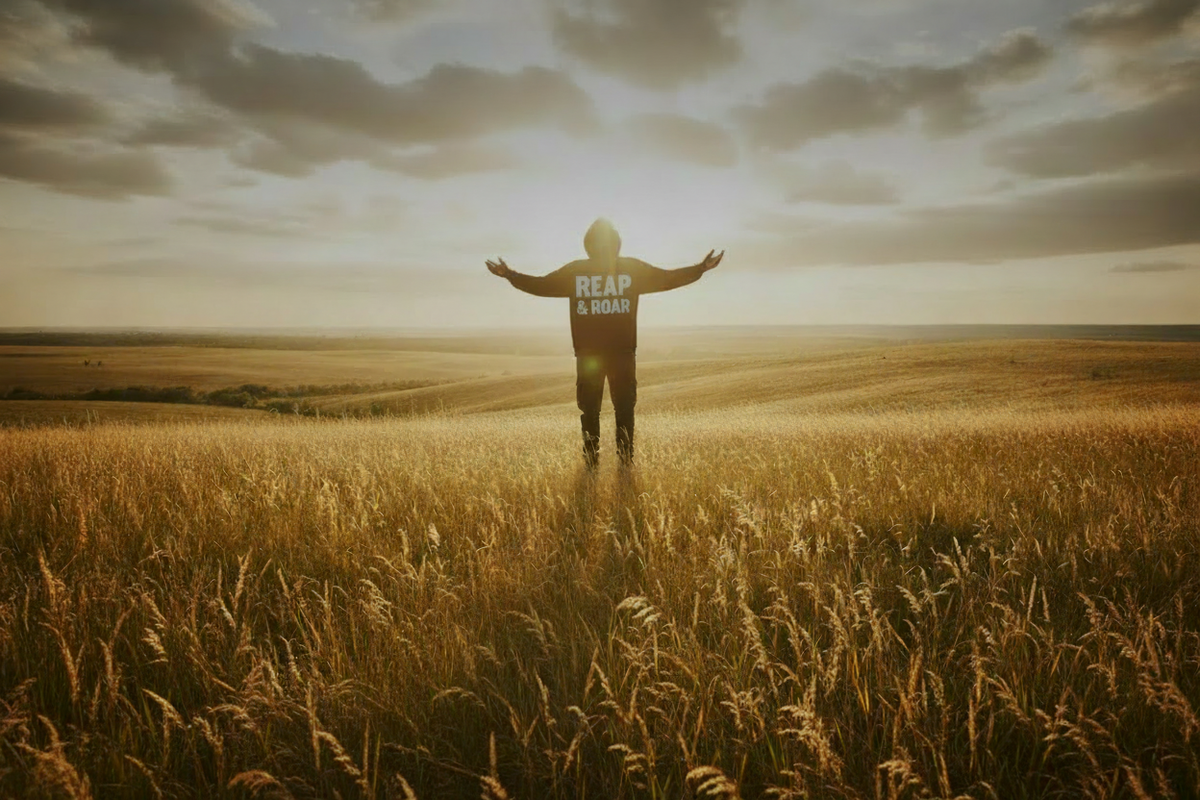 Person wearing Reap & Roar Christian apparel standing in a sunlit field